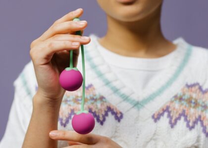 Close-up of a person holding purple kegel balls, illustrating pelvic floor trainer options for guide on trainers and apps.