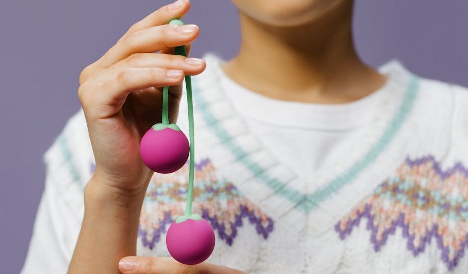Close-up of a person holding purple kegel balls, illustrating pelvic floor trainer options for guide on trainers and apps.