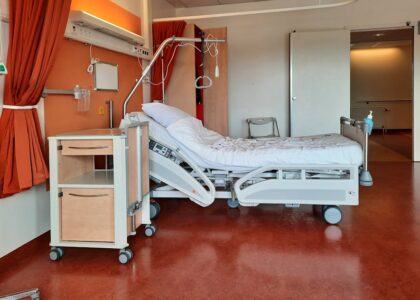 A clean and modern hospital room equipped with an adjustable bed and medical equipment.