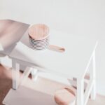A white wooden step stool with circular toppers bathed in natural sunlight, casting shadows.