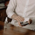 A person sanitizes their smartphone at a table, promoting healthy hygiene in home settings.