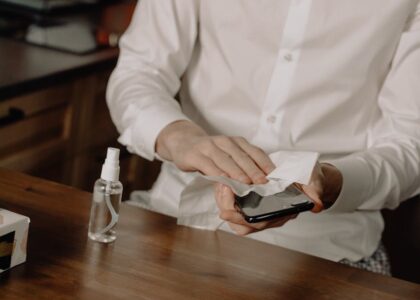 A person sanitizes their smartphone at a table, promoting healthy hygiene in home settings.