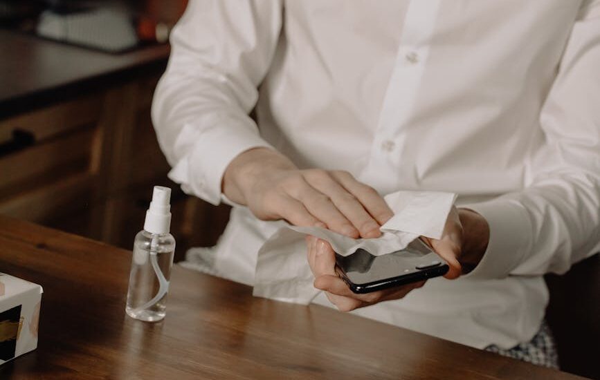 A person sanitizes their smartphone at a table, promoting healthy hygiene in home settings.