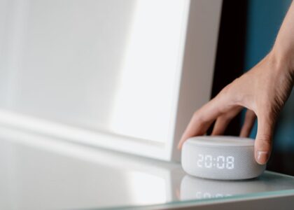 A hand adjusting a white noise machine on a table, relevant to white noise machines.