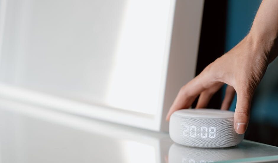 A hand adjusting a white noise machine on a table, relevant to white noise machines.