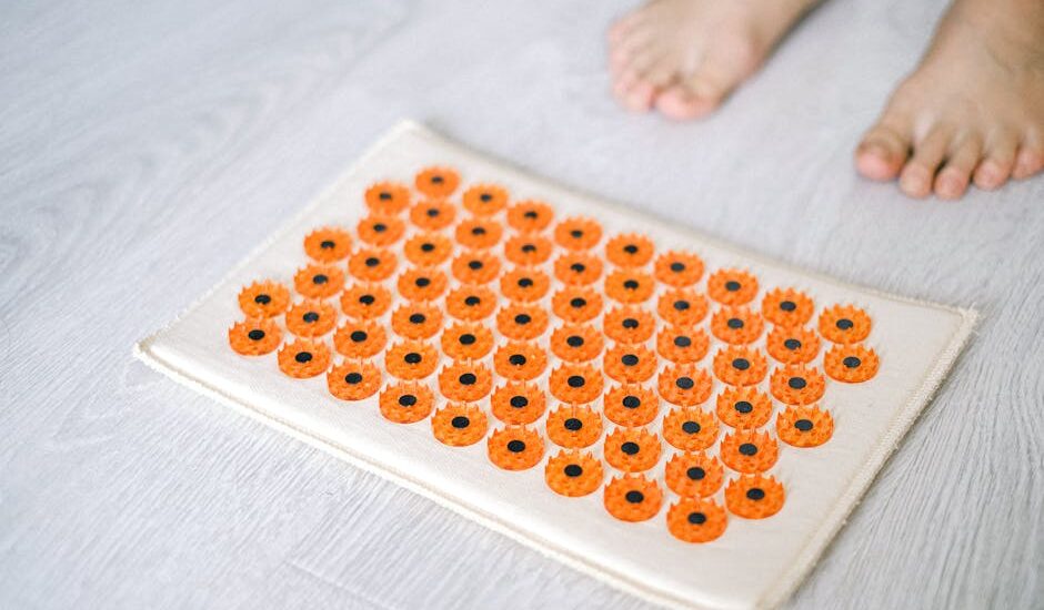 Close-up of a foot acupressure mat on a wooden floor, ideal for relaxation therapies.