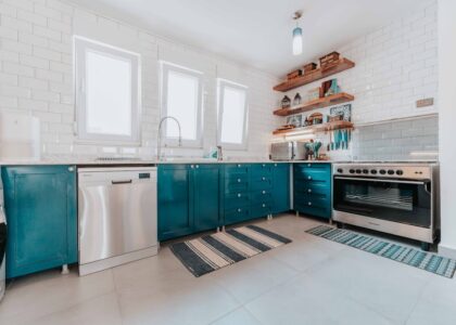 Contemporary kitchen with blue cabinets and striped anti-fatigue mats placed in front of the sink and stove, illustrating options for kitchen comfort in anti-fa