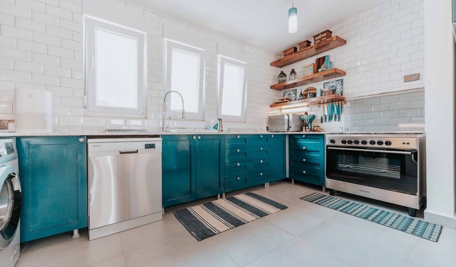 Contemporary kitchen with blue cabinets and striped anti-fatigue mats placed in front of the sink and stove, illustrating options for kitchen comfort in anti-fa