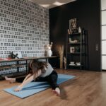 A woman performing a stretching exercise on a yoga mat in a stylish indoor space.