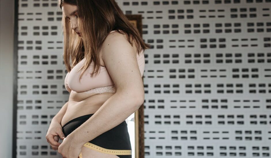 Confident young woman measures her hips in a stylish interior, embracing body positivity.