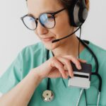 Medical professional with headset and stethoscope during a telemedicine consultation.