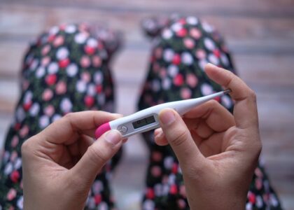 Hands holding a digital thermometer with a pink tip, illustrating a key device featured in the best digital thermometers 2026 guide.