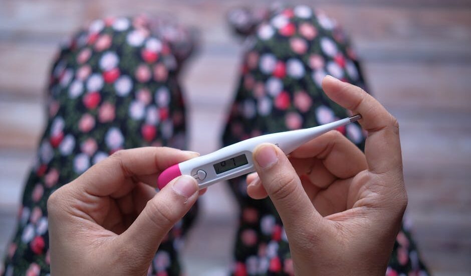 Close-up of hands holding a digital thermometer against a blurred background.
