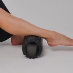 best electric foam roller — Close-up of a leg using a foam roller for stretching and muscle relief in a studio setting.