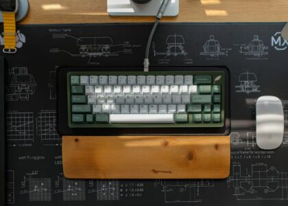 A compact ergonomic keyboard with green and white keys and a wooden wrist rest, shown on a desk for a 2026 ergonomic keyboard guide.