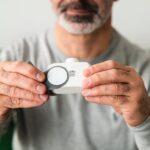 A close-up of a man using a handheld air quality analyzer, focusing on health and technology.