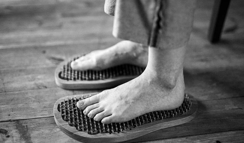 Black and white photo of feet receiving a relaxing massage on wooden reflexology boards.