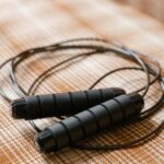 A black jump rope coiled on a patterned plaid surface, highlighting fitness equipment.
