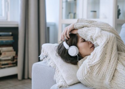 A young woman in a knitted sweater relaxing with headphones, conveying a sense of calm and introspection.