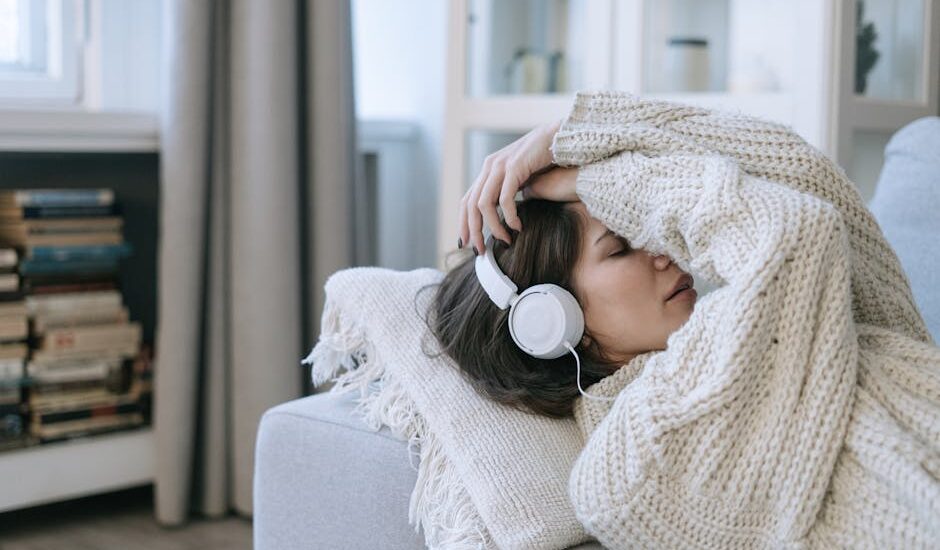 A young woman in a knitted sweater relaxing with headphones, conveying a sense of calm and introspection.