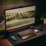 Elegant computer setup featuring keyboard, monitor, and plants on a wooden desk. Perfect for tech and workspace enthusiasts.
