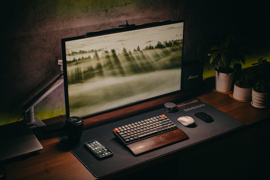 Elegant computer setup featuring keyboard, monitor, and plants on a wooden desk. Perfect for tech and workspace enthusiasts.