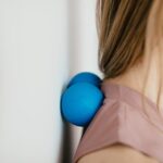 A person uses two blue massage balls against a wall for neck relief, illustrating a technique featured in the best neck massagers 2026 guide.