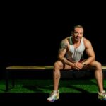 Fit male athlete in gym resting on bench, showcasing strength and motivation.