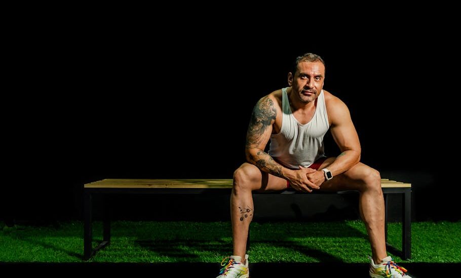 Fit male athlete in gym resting on bench, showcasing strength and motivation.