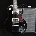 A sleek black electric guitar and amp captures the essence of modern rock music gear.