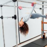 Fit woman doing pilates exercise on reformer equipment in a fitness studio.