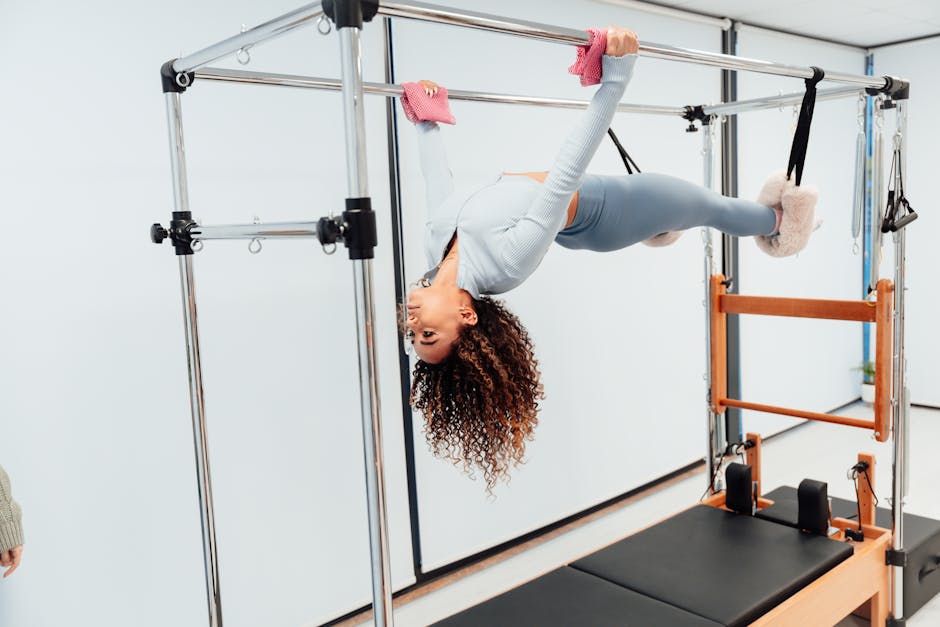 Fit woman doing pilates exercise on reformer equipment in a fitness studio.