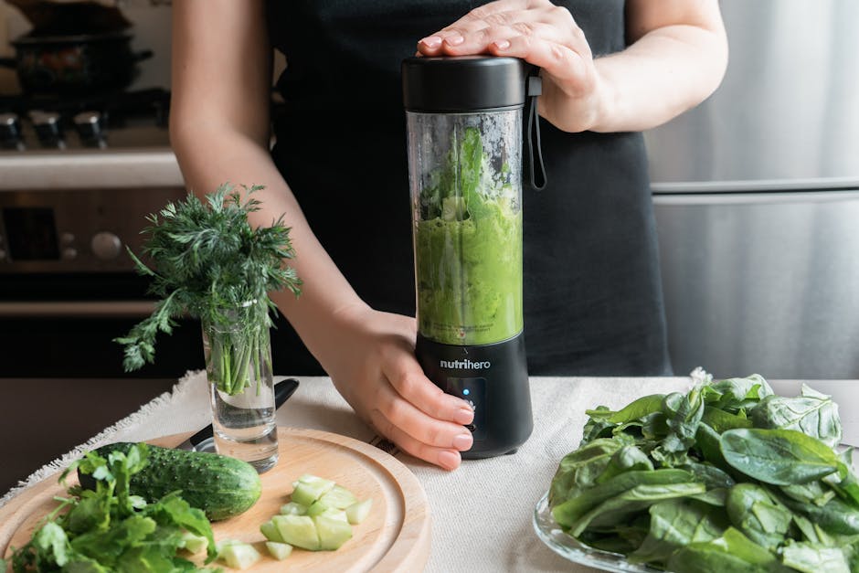 A person making a healthy green smoothie with fresh vegetables in a modern kitchen.