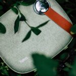 Top view of portable contemporary wireless speaker to play music placed on green grass