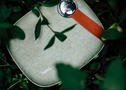 Top view of portable contemporary wireless speaker to play music placed on green grass
