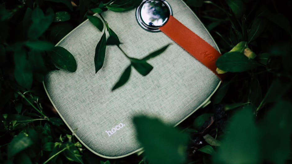 Top view of portable contemporary wireless speaker to play music placed on green grass