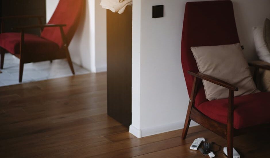 Stylish red armchair with wooden legs in a warm, minimalist living room setting.
