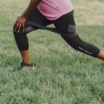 A woman performs resistance exercises outdoors, focusing on leg strength.
