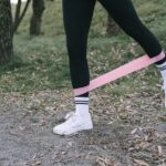 Close-up of person exercising with a pink resistance band outdoors.