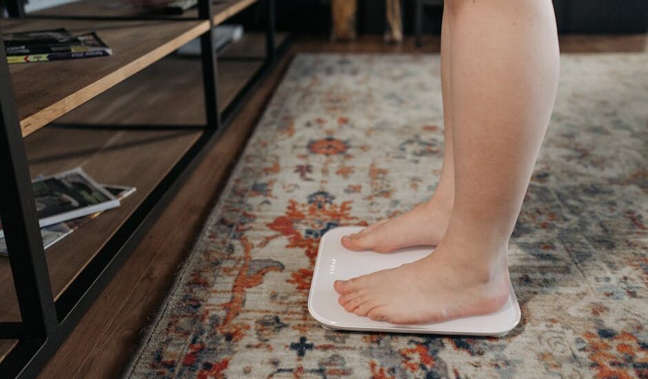 A person stands barefoot on a digital smart scale in a home setting, illustrating body composition tracking for the best smart scales guide.