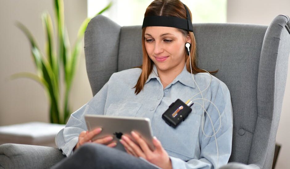 A woman engages with a biofeedback device for stress management while seated comfortably.