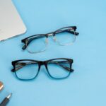 Stylish glasses and tech accessories arranged on a bright blue background, perfect for fashion and lifestyle themes.