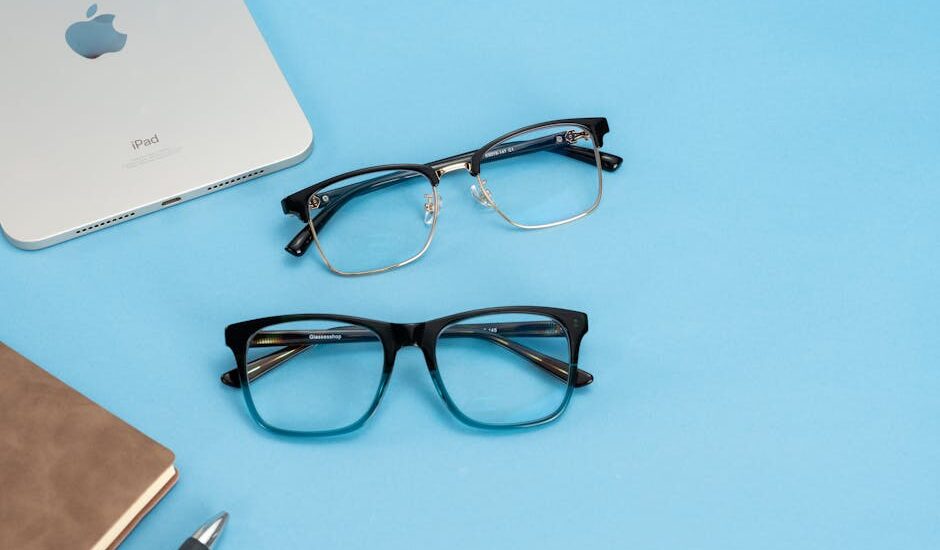 Stylish glasses and tech accessories arranged on a bright blue background, perfect for fashion and lifestyle themes.