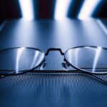 A pair of eyeglasses rests on a glowing screen, illustrating the comparison of blue light glasses and screen filters.