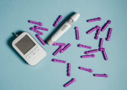 Top view of lancets scattered around blood glucose meter and lancing device on blue background
