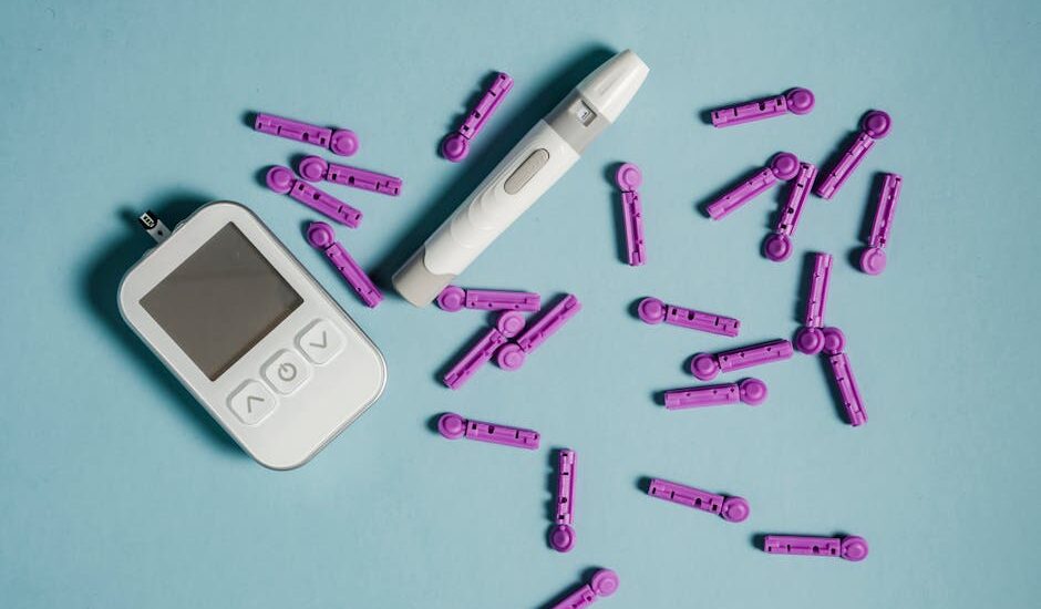 Top view of lancets scattered around blood glucose meter and lancing device on blue background