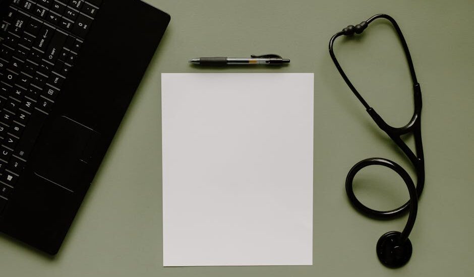 Medical workspace featuring a blank paper, stethoscope, and laptop from above.