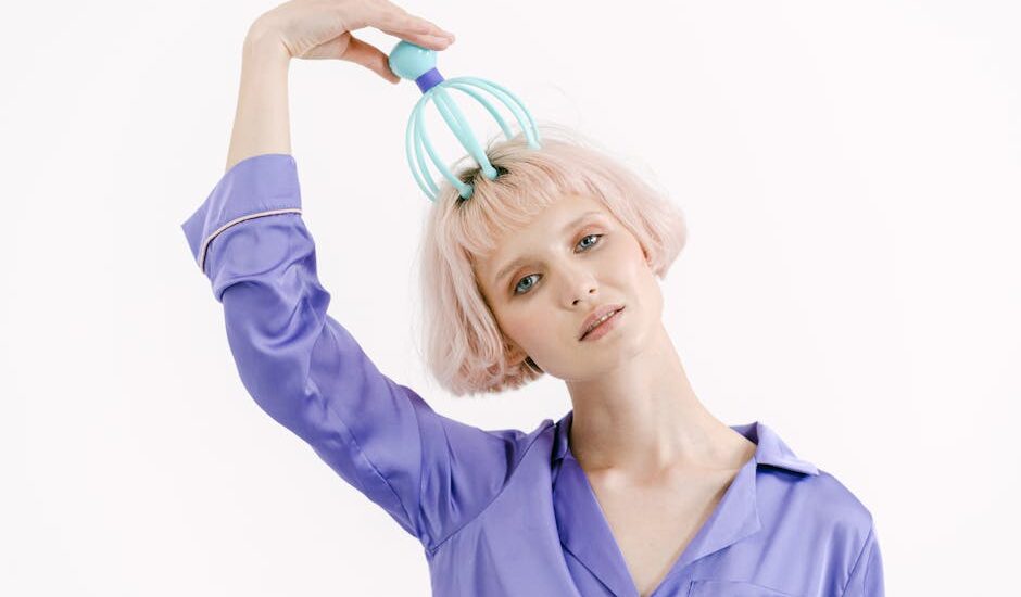 Person in a purple shirt using an electric scalp massager on their head, illustrating electric scalp massager use for the article topic.