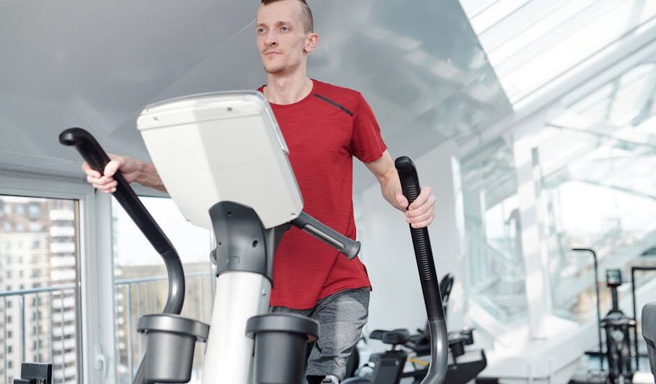 Man with a prosthetic leg working out on an elliptical trainer in a bright, modern gym.