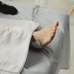 A person receives electrical stimulation therapy on their ankle, illustrating EMS vs TENS device use for pain relief.